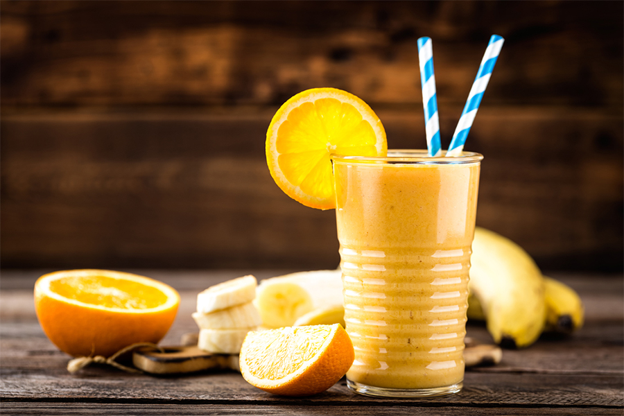 Glass of Mango Orange Creamsicle Smoothie with orange slice garnish