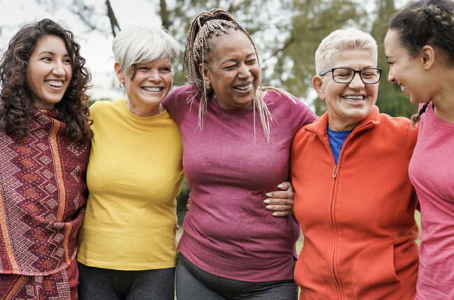 Diverse group of women hugging side by side outside