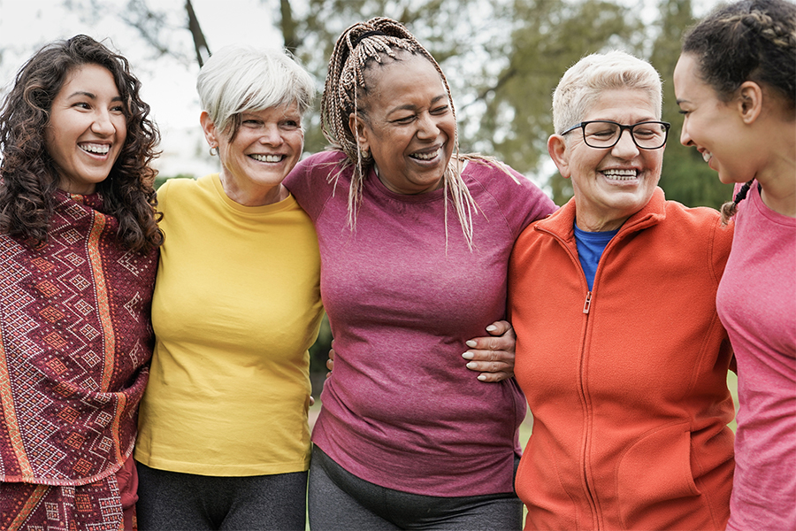 Diverse group of women hugging side by side outside