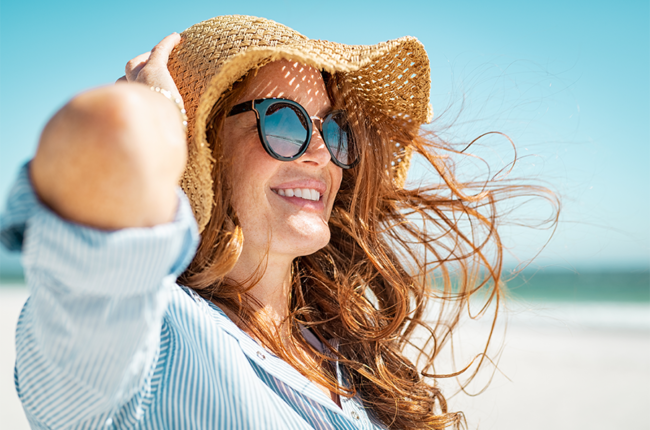 Redhead woman on the beach with sunglasses and a sunhat