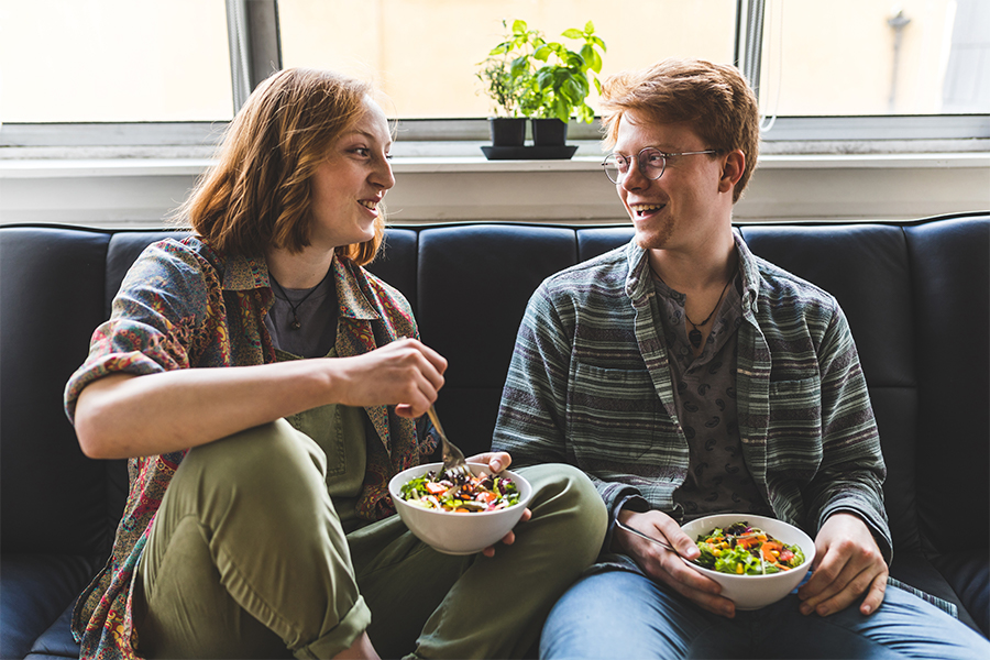 Couple eating healty salad at home on the sofa
