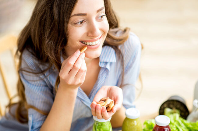 Closeup view from above of a woman eating brasil nuts with healthy food on the background