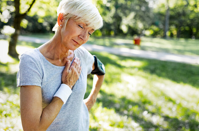 Senior woman with chest pain suffering from heart attack during jogging